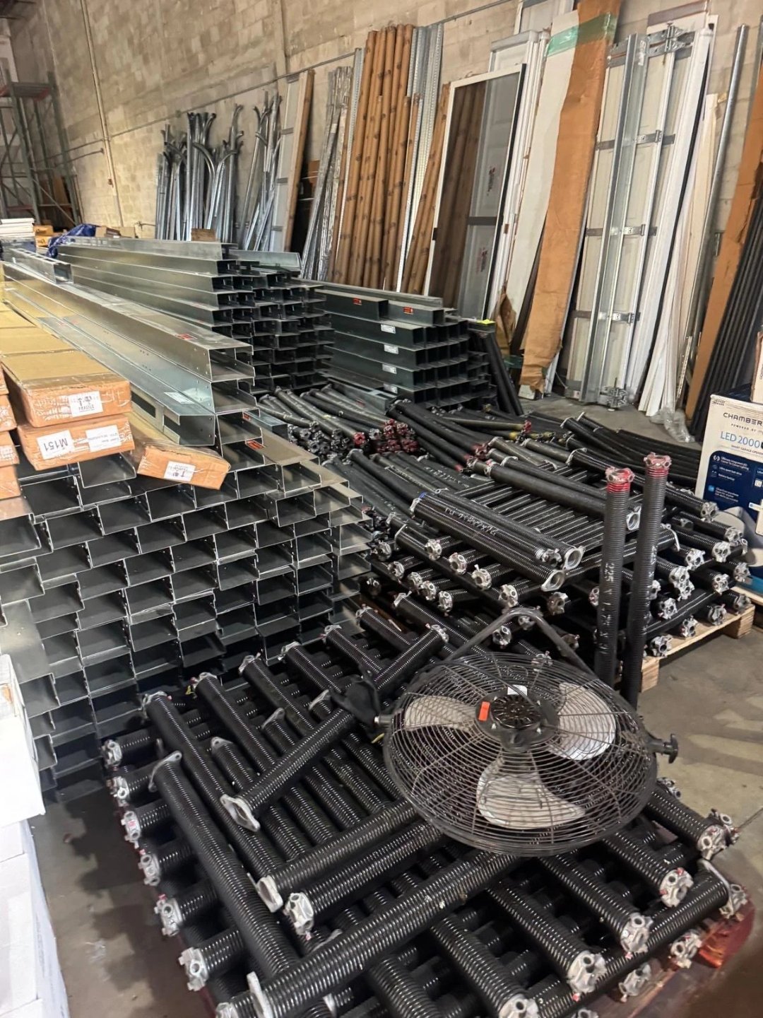 Steel door tracks and hardware stacked inside a workshop
